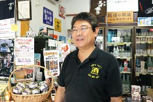写真：お酒がたくさん置かれたお店の中でお話をする西沢さん
