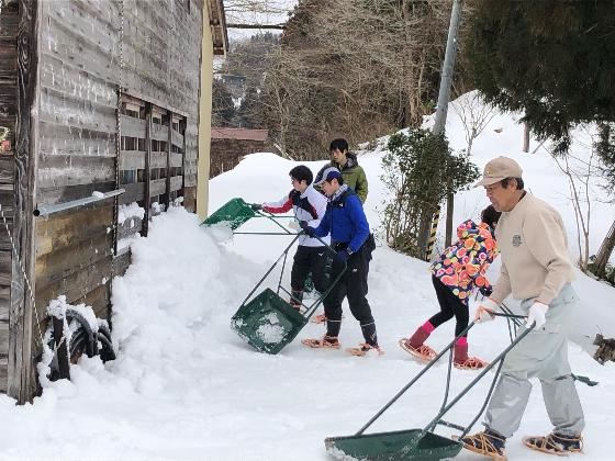 写真：スノーダンプを使いながら、民家の軒先に積もった雪を次々と運ぶメンバー