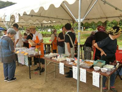 写真：テントの下で地域の方が唐あげや豚汁、炊き込みご飯などを販売しています