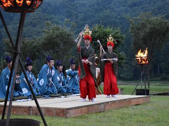 写真：赤いゆらいに天冠をかぶり、綾竹を打ち鳴らしながら踊る2人の女性