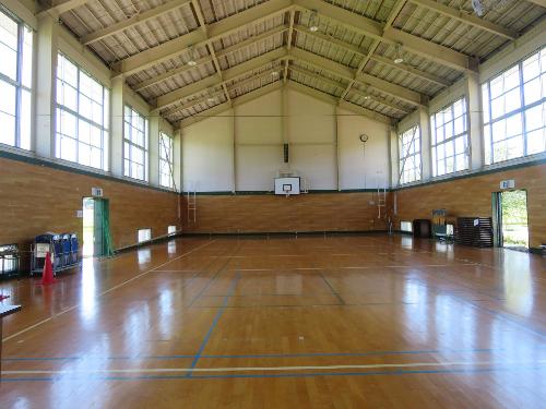 講堂（体育館）。バスケットボールコートが1面獲れ、壁にはゴールが備え付けられています。