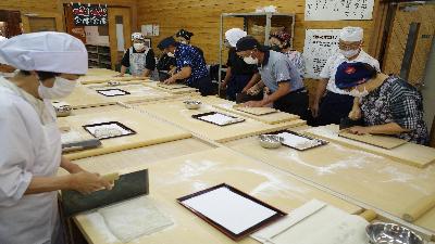 写真：打ったそばを包丁で細長く切る練習をするそば打ち同好会の皆さん