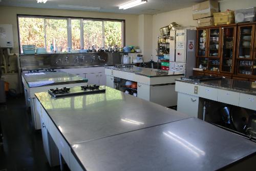 調理台兼作業台が4台ある調理実習室。奥には食器棚や冷蔵庫があります
