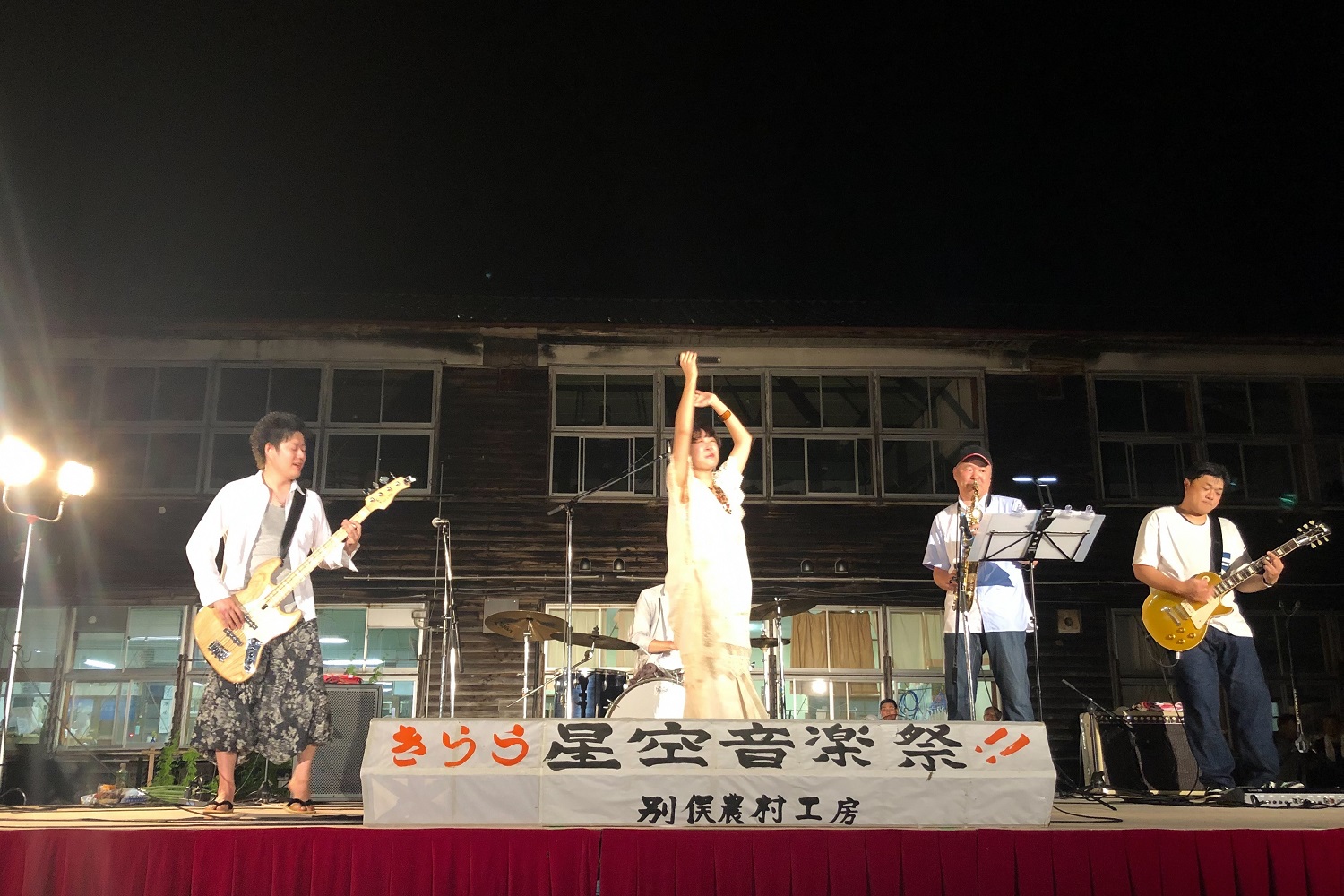 写真：星空音楽祭で、木造の旧校舎の前に設置されたステージで演奏する出演者の皆さん