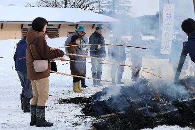 写真：炎が落ち着いたさいの神に、持ち寄ったするめや餅を焼いている住民の皆さん