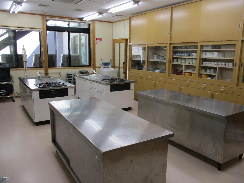 写真：調理実習室。ガスコンロのついた調理台が2つと作業用の台が2つあります
