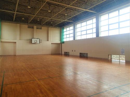 講堂（体育館）。バスケットボールコートが1面獲れ、壁にはゴールが備え付けられています。