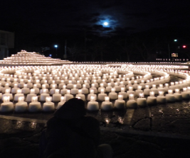 写真：コミセンの駐車場一面に敷き詰められたキャンドル。夜の闇に、いくつものキャンドルの光が揺らめいています