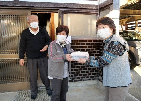 写真：玄関先でお弁当を笑顔で受け取るご夫婦