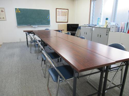1階のカーペット敷きの会議室。部屋の中央に机が並んでいます