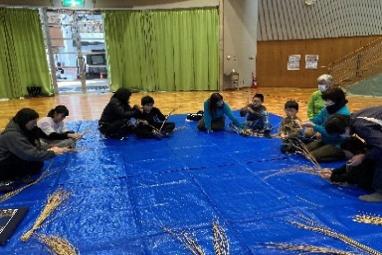 写真：地域の高齢者などが講師となり、親子でしめ縄づくりをしているところ