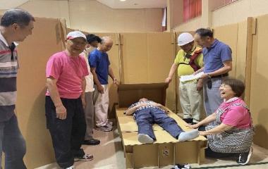 写真：地域住民らが防災訓練で段ボールベッドを作成。ベッドの寝心地を試しています。