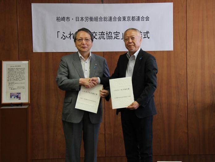 市長と岡田連合東京会長が協定書を持ち、握手している写真