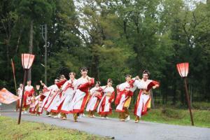 赤と白と金色の衣装を着た人たちが2列に並んで、よさこいを踊っている写真