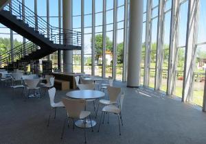 前面ガラス張りの休憩スペースにはテーブルと椅子が設置され開放感があるホワイエ・展示室の写真
