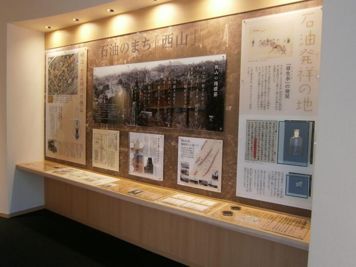 西山の石油発祥や友好都市である中国わいあんを紹介するポスターなどが展示されている西山ふるさと館展示室の写真