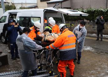 写真：地域住民をストレッチャーに載せた状態で避難訓練を行う様子