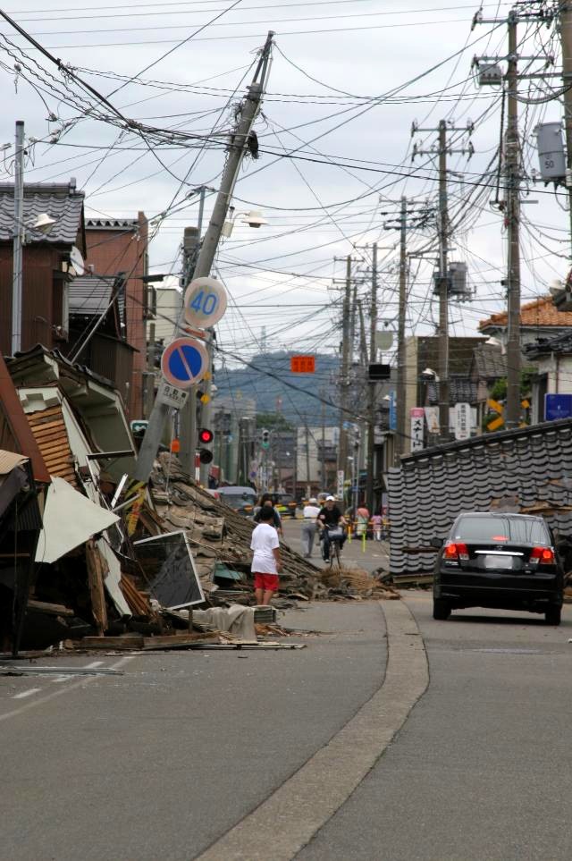 倒壊し、道路をふさいだ家屋の写真