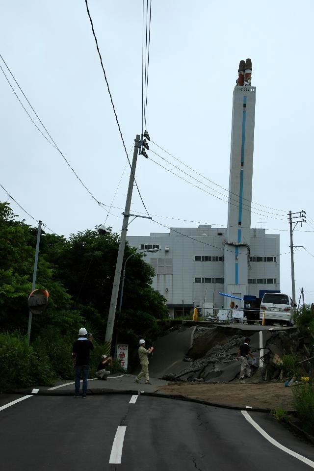 クリーンセンターの煙突の破断と大きく陥没した道路の写真