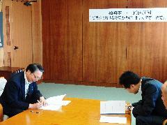 協定書に調印する増井上越地区営業部長と会田市長の写真