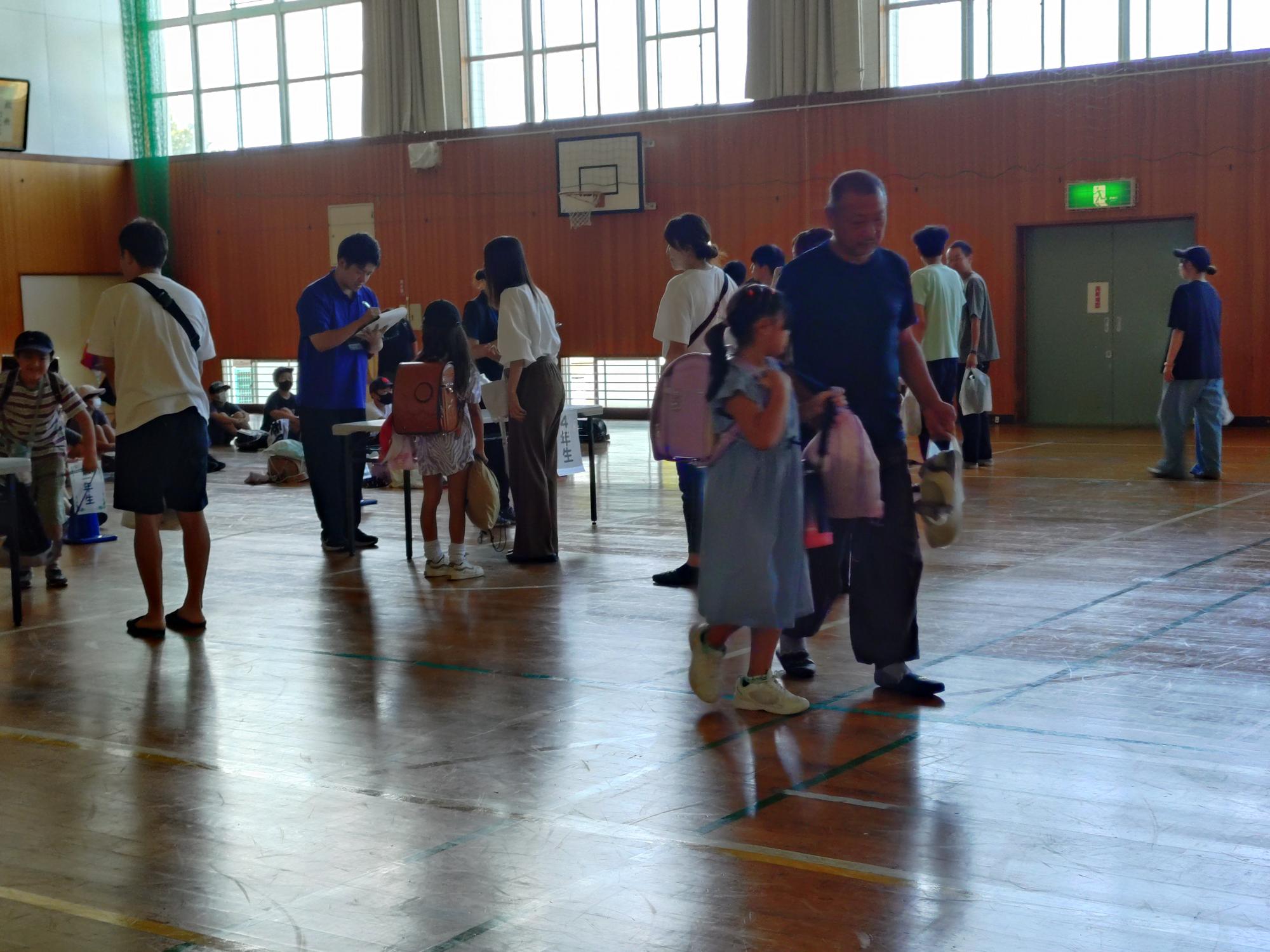 写真：小学校の体育館で、保護者の確認などを行い、児童を引き渡す訓練をしているところ