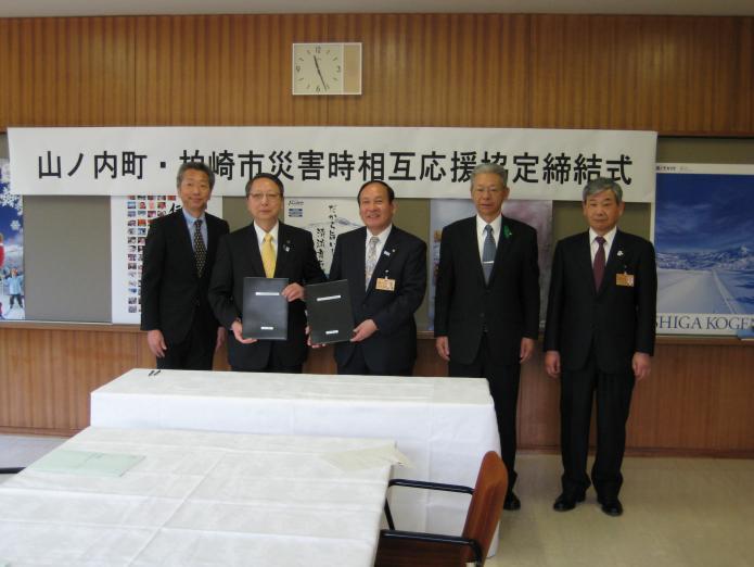 竹節山ノ内町長と会田市長をはじめ、締結式に出席した関係者が1列に並んでいる様子の写真