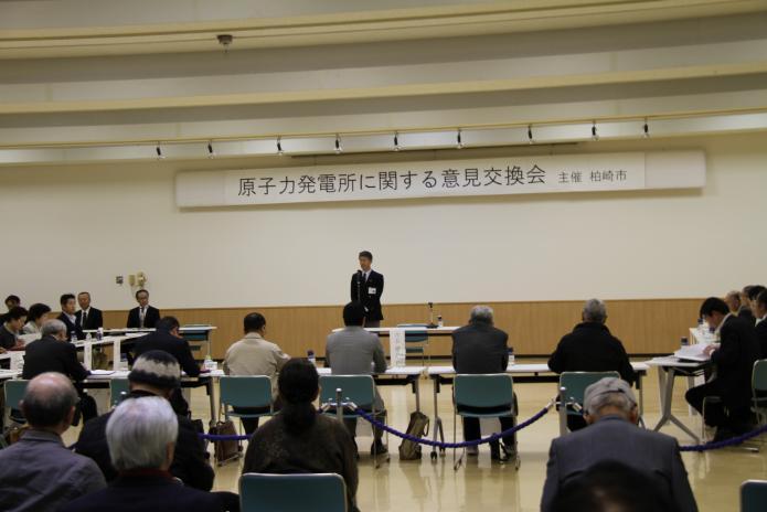 原子力発電所に関する意見交換会の会場で意見発表者の方々の前で説明をする市長の写真