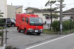 赤い消防車が駐車場から道路へ向かっている写真