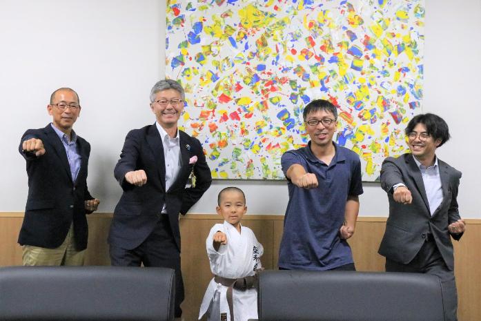 市長が目崎さん親子と柏崎空手道連盟会長、コーチと並んで空手の形をしながら記念撮影している様子