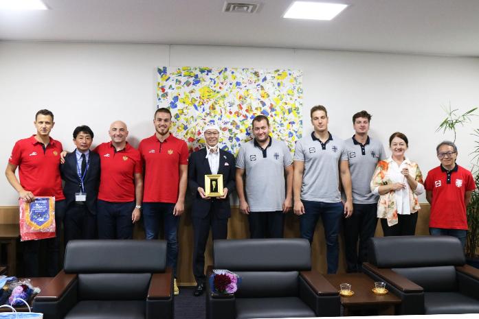 水球キャップを被った市長がモンテネグロとセルビア共和国の水球男子チームの選手と並んで記念撮影している様子
