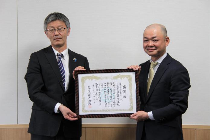 企業版のふるさと納税に対する感謝状を市長と企業の代表者が一緒に持ち映っている写真