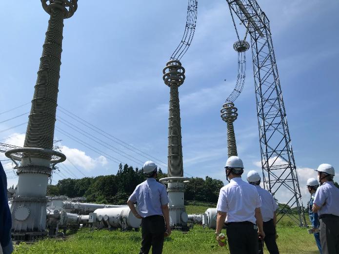 UHV機器試験場の設備の前で、市長が説明を受けている様子