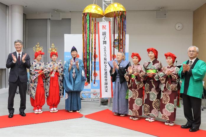 市長が綾子舞の演者と並び、くす玉を割ってユネスコ登録をお祝いしている様子
