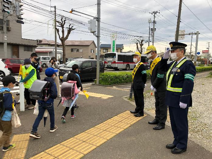 市長が交通安全の帽子とタスキを身に着けて、登校する児童らに声を掛けている様子