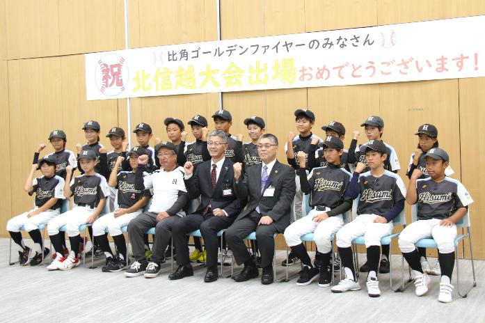 市長と教育長が学童野球チームの比角ゴールデンファイヤーの選手・監督と並んで記念撮影している様子