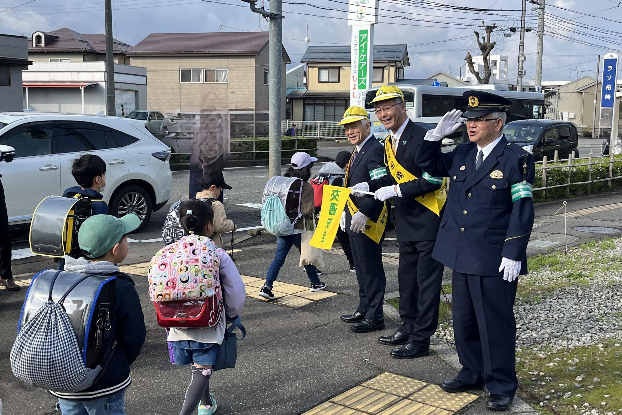 交通立哨をしている市長、柏崎交通安全協会会長、柏崎警察署長と通学する小学生