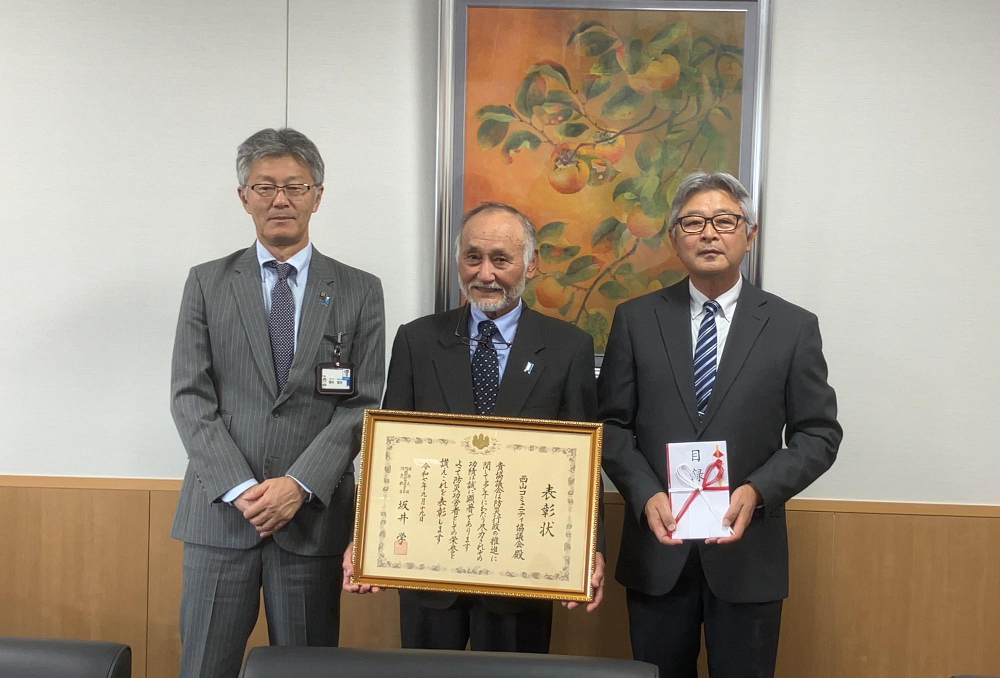 写真：市長と西山コミュニティ協議会関係者が表彰状と目録を持っています