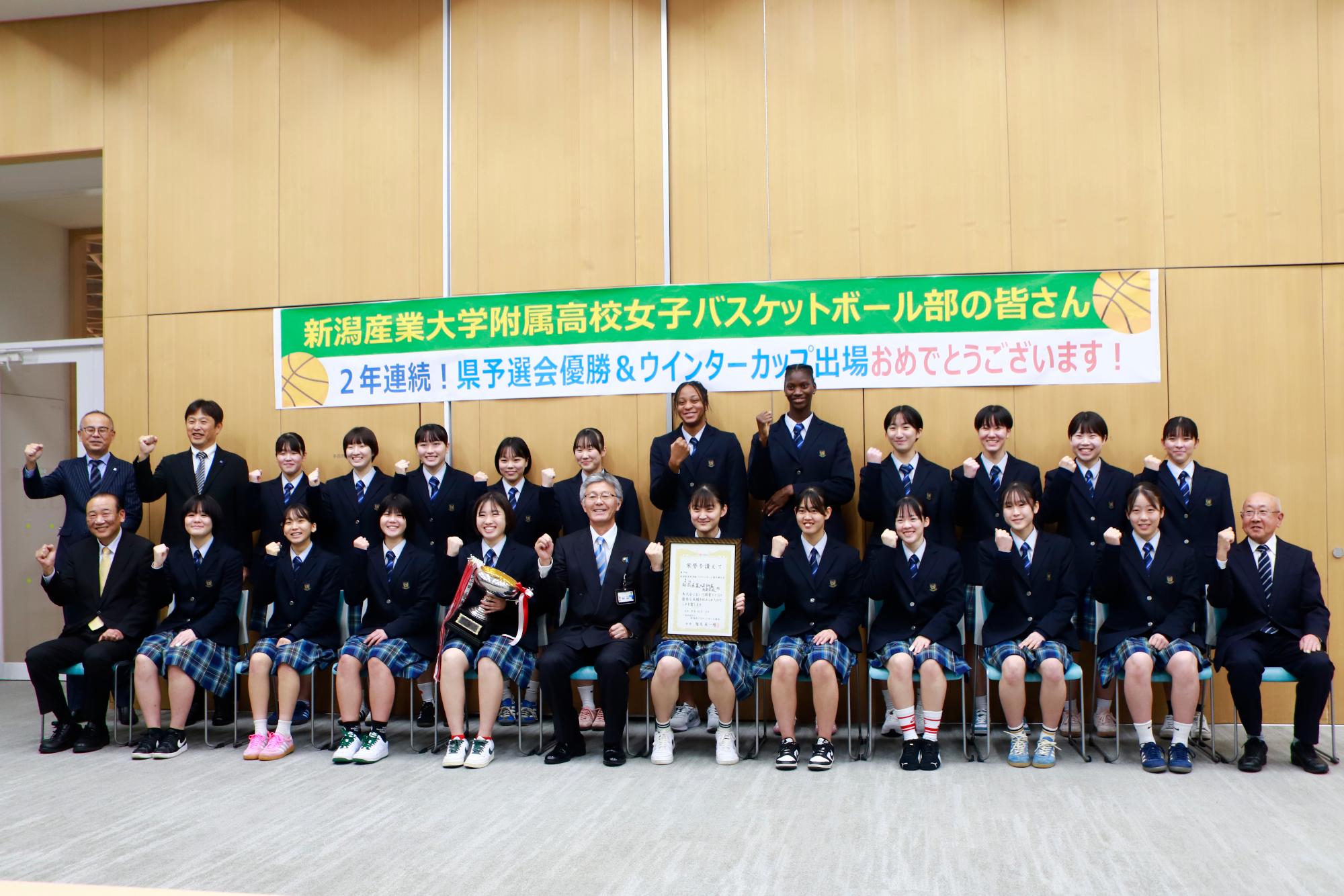 市長と産業大学附属高校女子バスケットボール部とガッツポーズをして写っている。