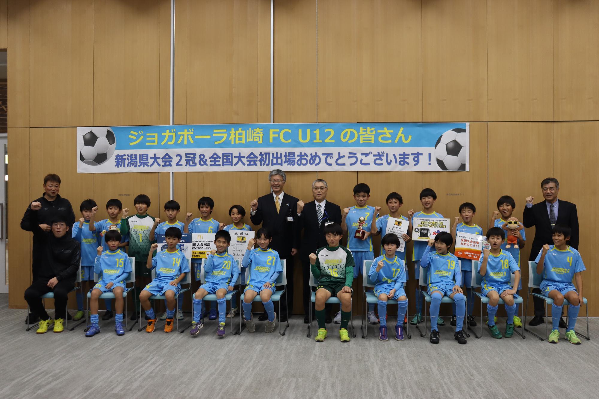 写真：市長と教育長が全国大会に出場する子どもたちと一緒にガッツポーズをしています