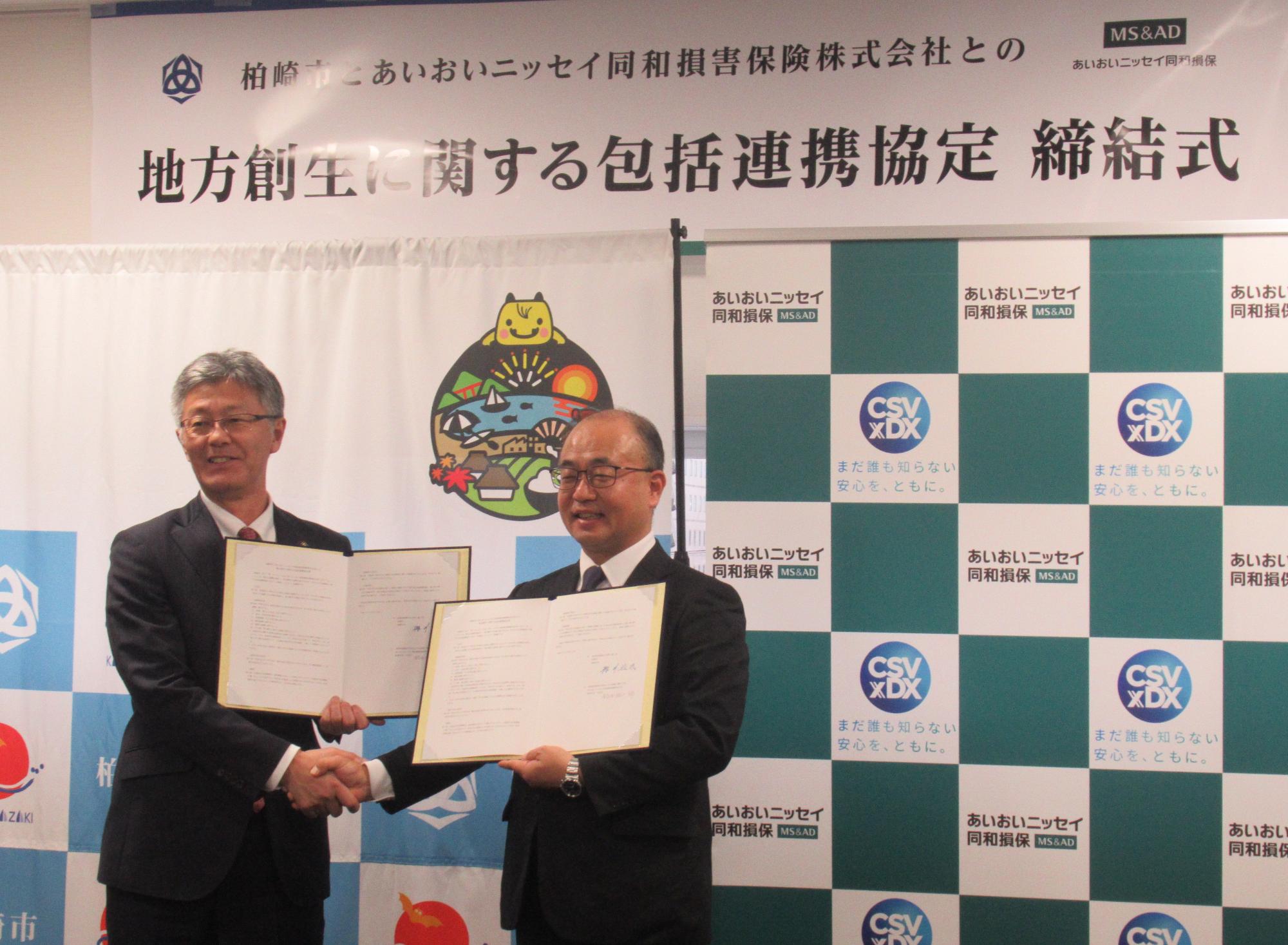 写真：あいおいニッセイ同和損害保険株式会社の役員と市長が握手を交わしています