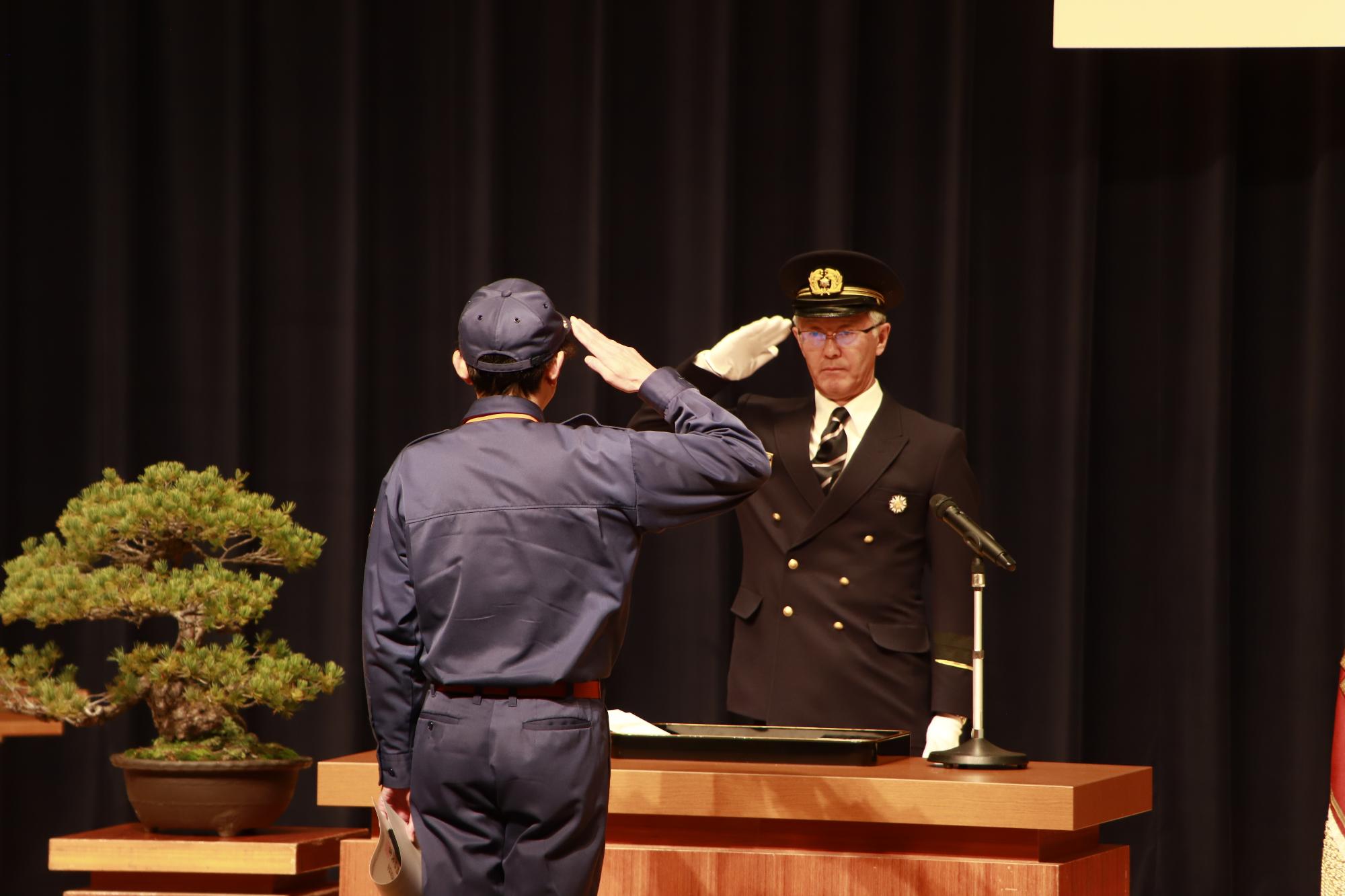 市長が消防団に表彰状を渡し、敬礼している。