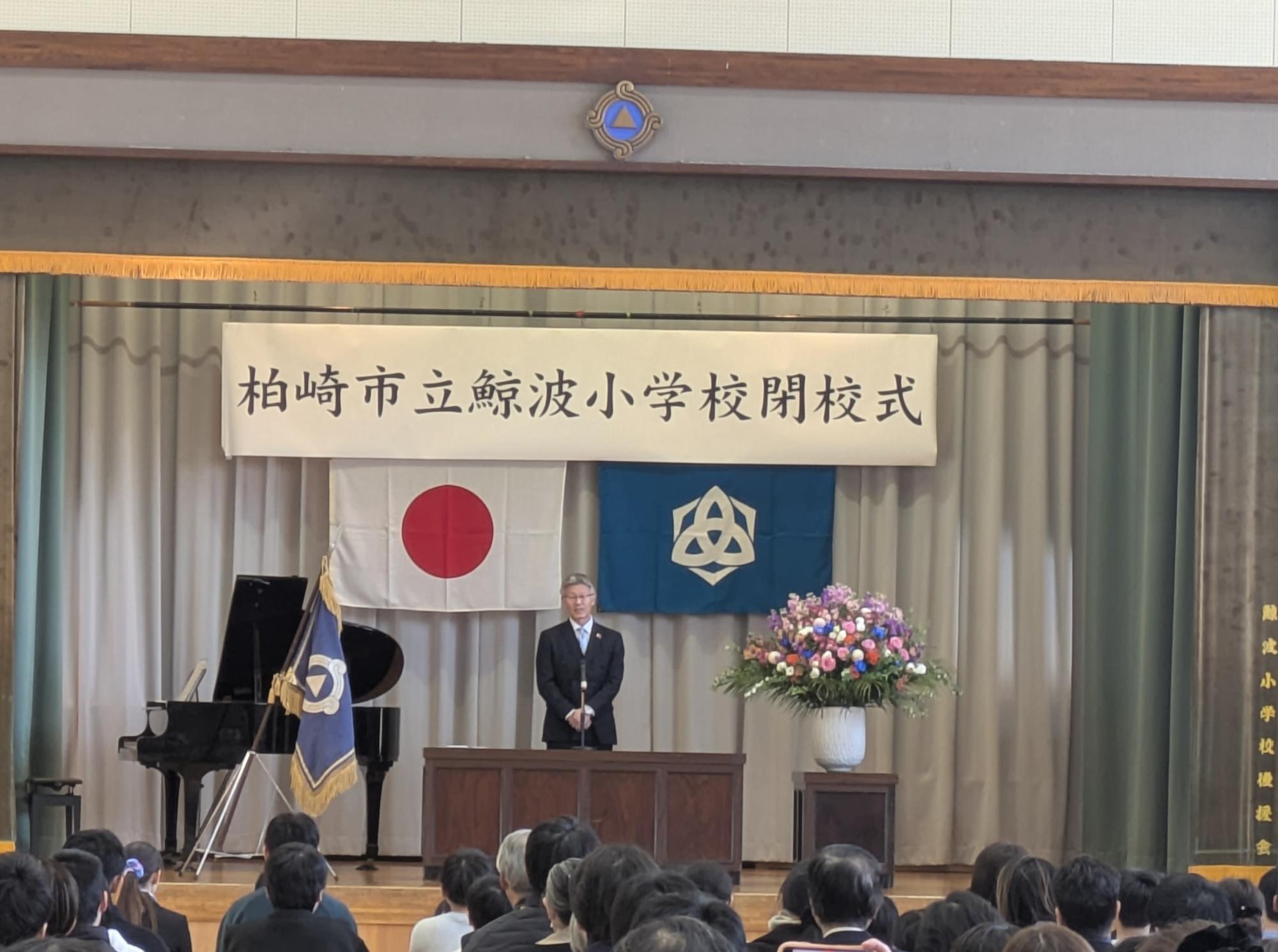 写真：鯨波小学校体育館で、市長が壇上から式辞を述べているところ