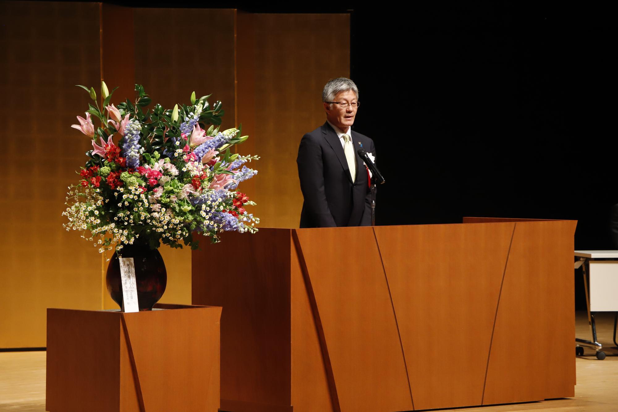 写真：市長がステージ上から20歳を迎えた若者にお祝いの言葉を述べているところ