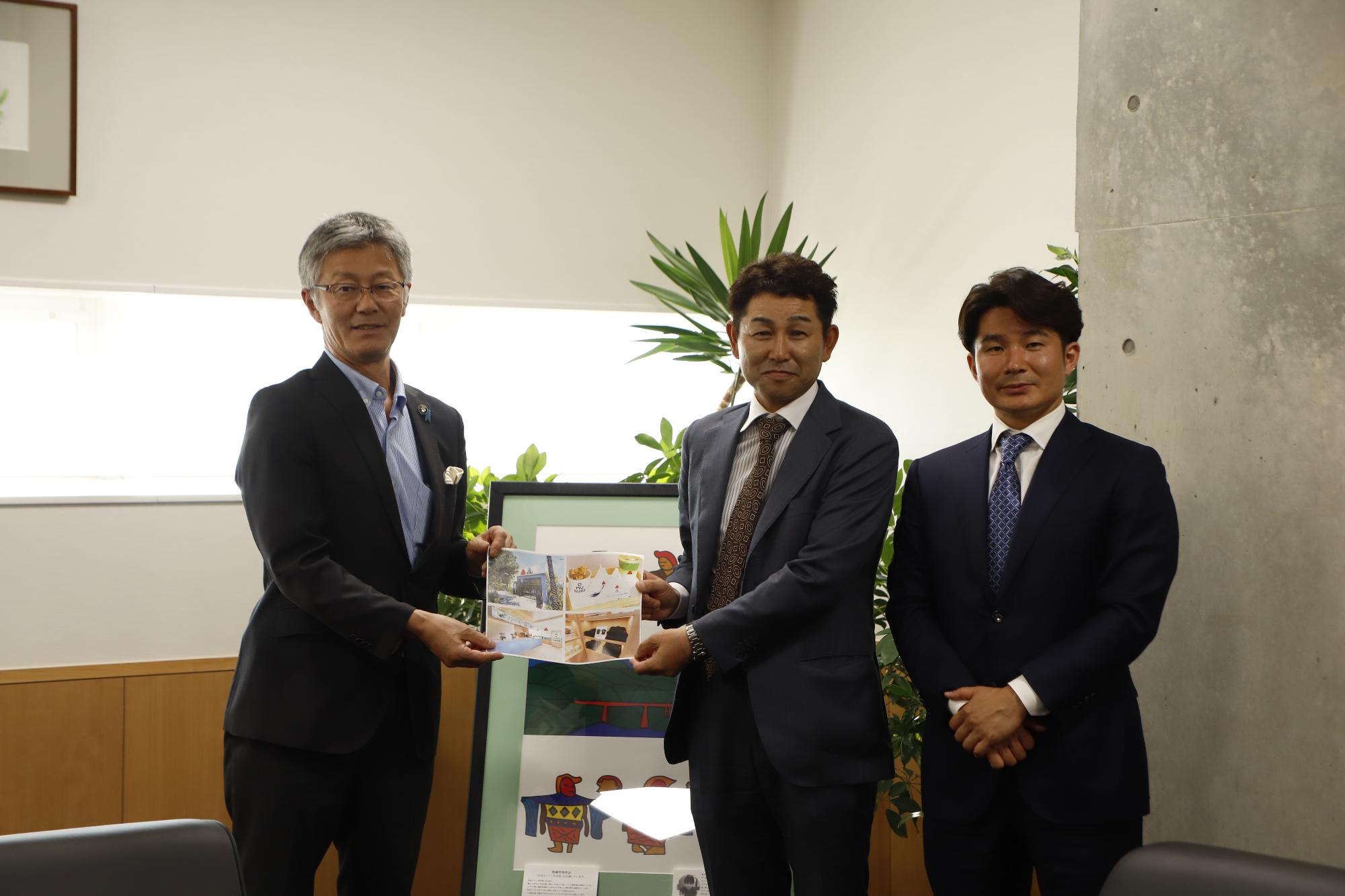 写真：櫻井市長と山波農場の山波社長が会社のイメージ写真を持ち、その隣に百農社の西田社長が並んでいます。
