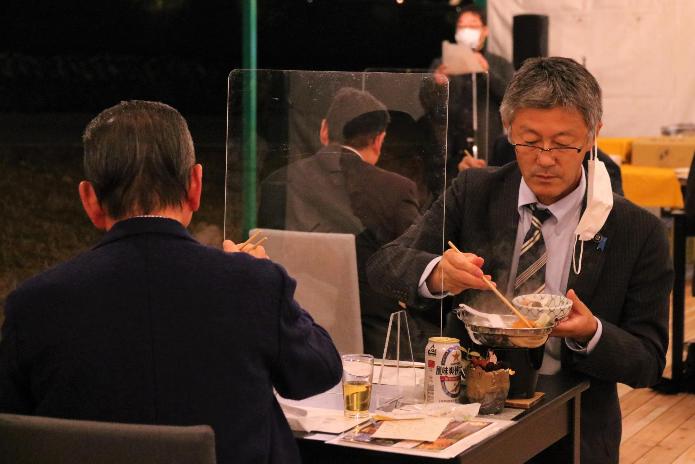 赤坂山紅葉ダイニングの料理を楽しむ市長。向かいの人との間には透明アクリル板が設置されています。