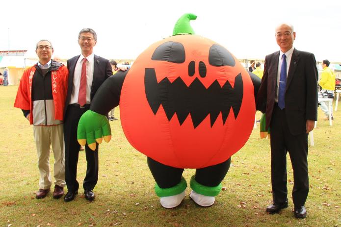 ハロウィンのかぼちゃの巨大バルーンと並んで立つ櫻井市長と與口議員ら