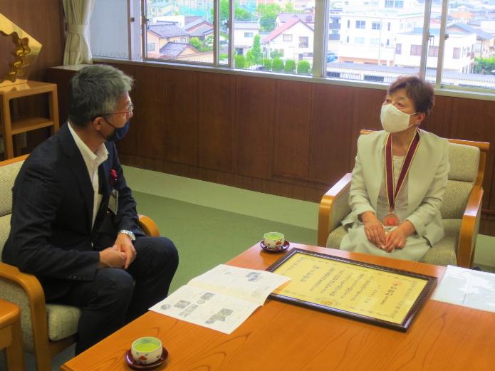 応接室で対談する佐藤会長と市長。机にはサポーター章の賞状が置かれています。