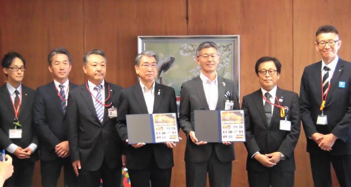 日本郵便から贈呈された切手フレームを手にする市長と議長の写真