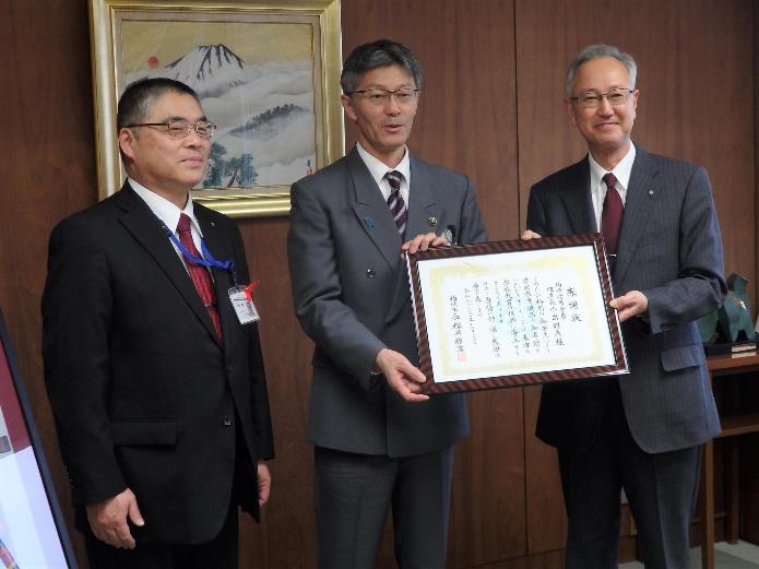 感謝状を一緒に持つ小出理事長と櫻井市長の写真。市長の隣には教育長が並んでいます