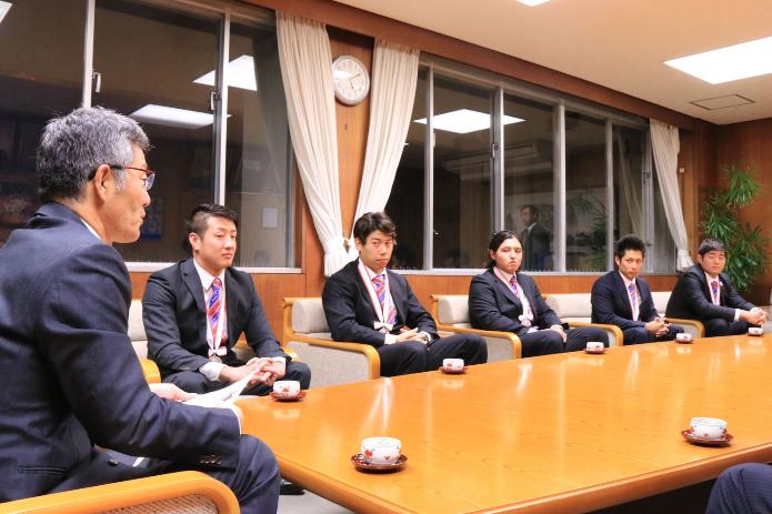 応接室のテーブルの周りに座るスーツを着た水球選手と櫻井市長
